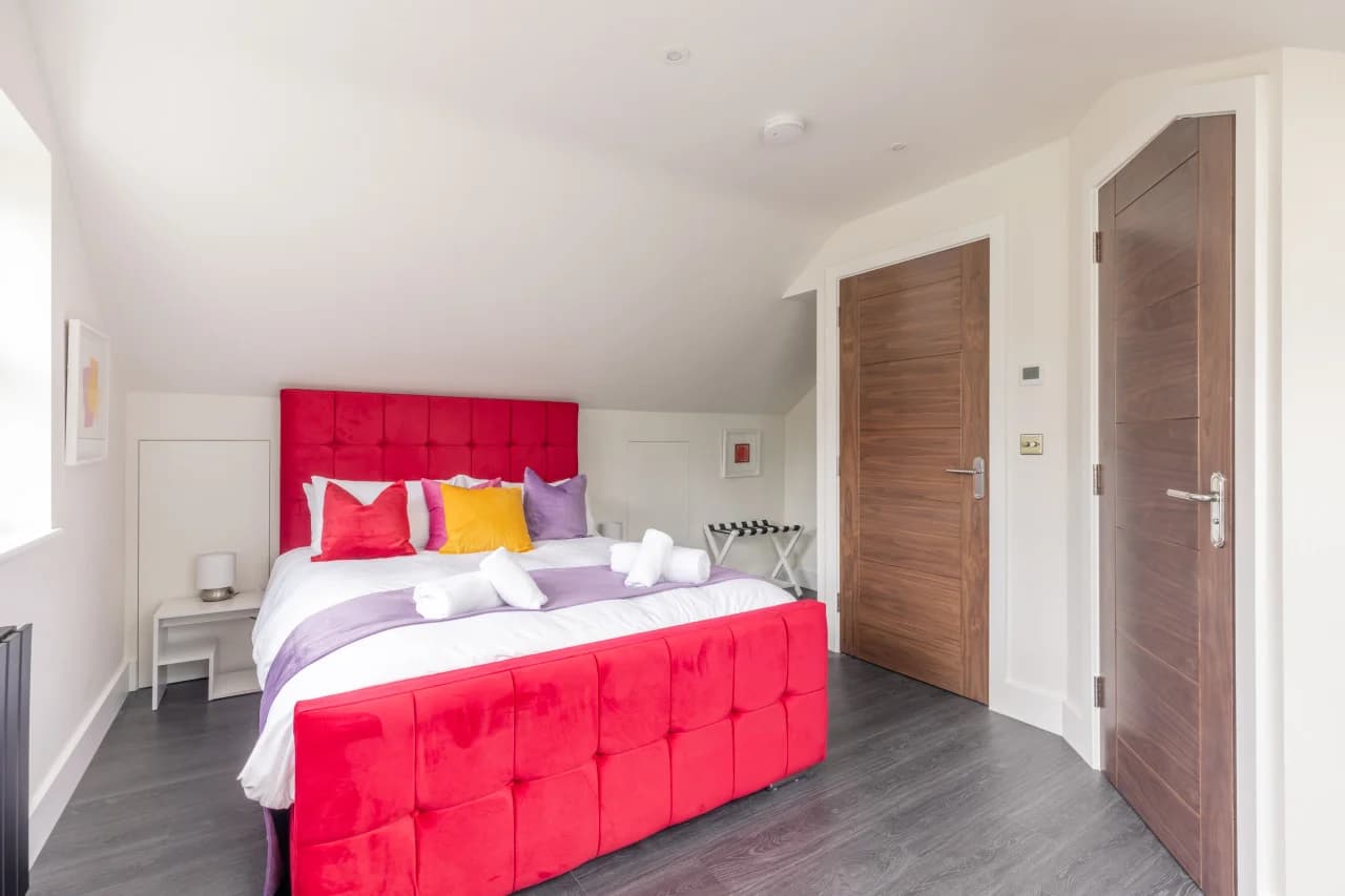King bedroom with red upholstered bed and walk-in wardrobe