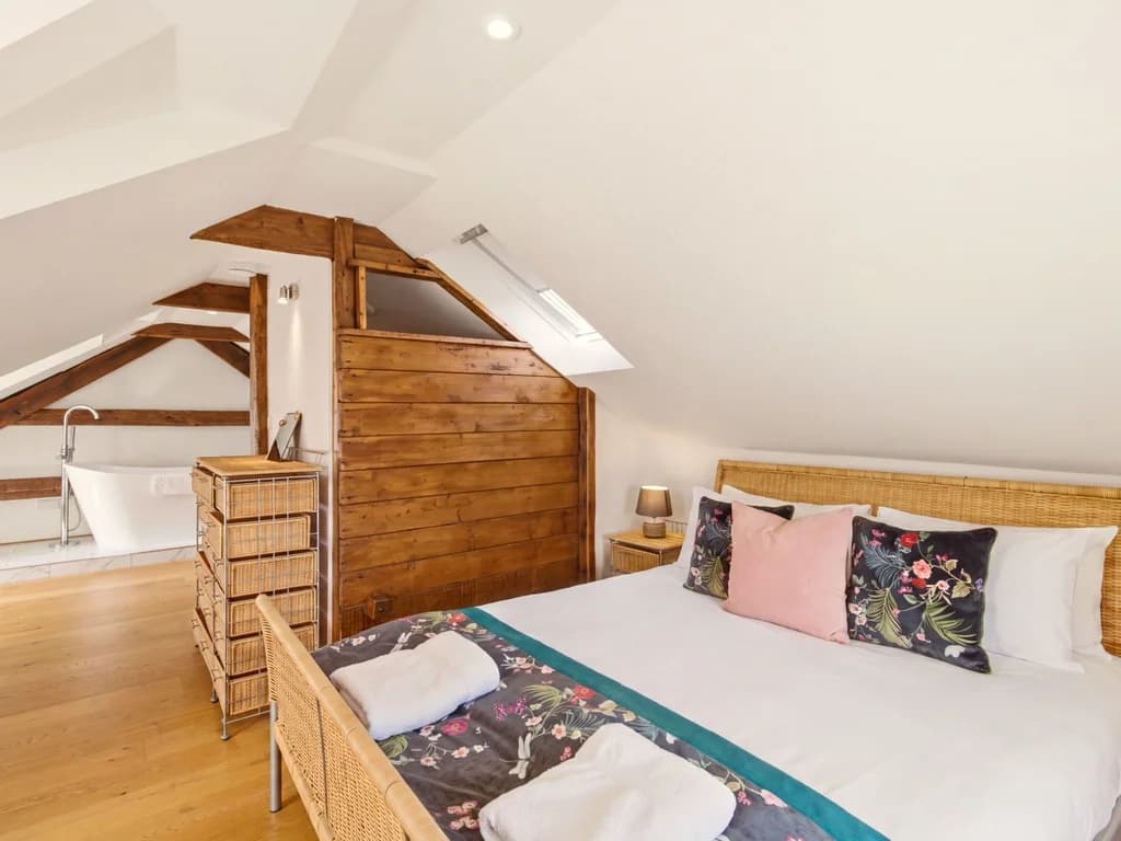Hayloft bedroom with queen-size bed and freestanding bath nearby
