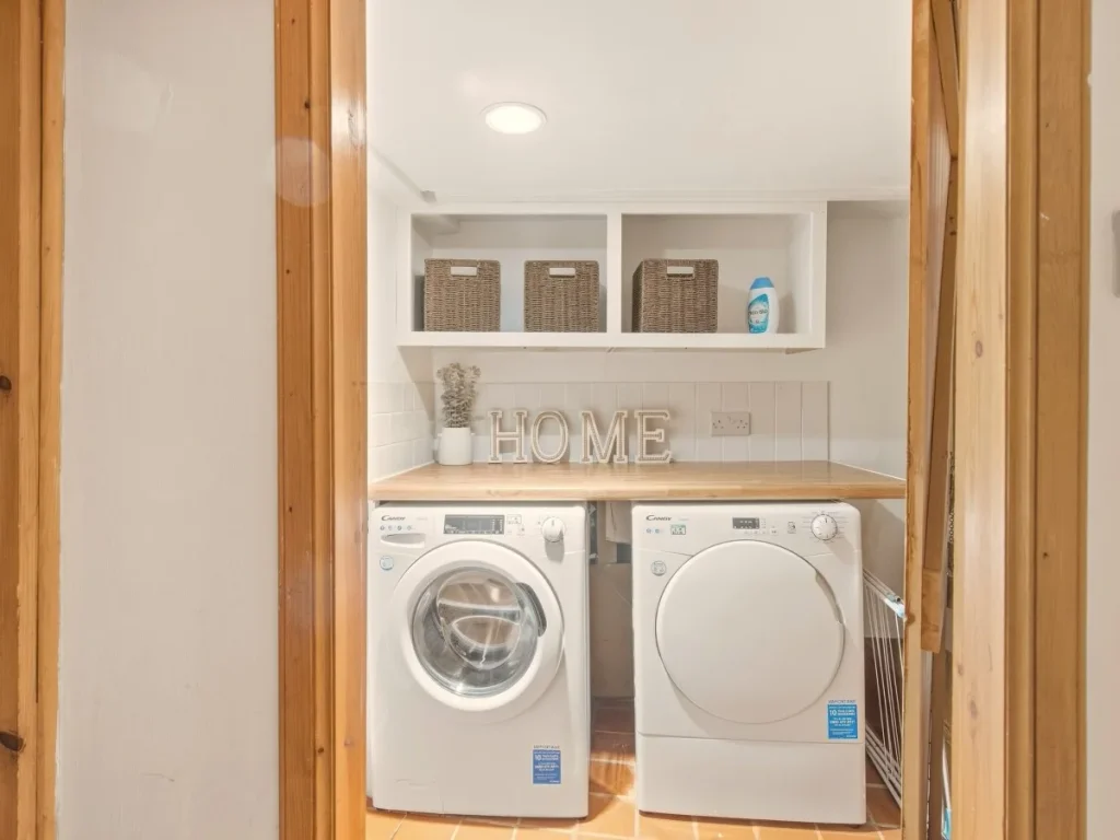 Separate laundry area with washing machine, tumble dryer and storage.