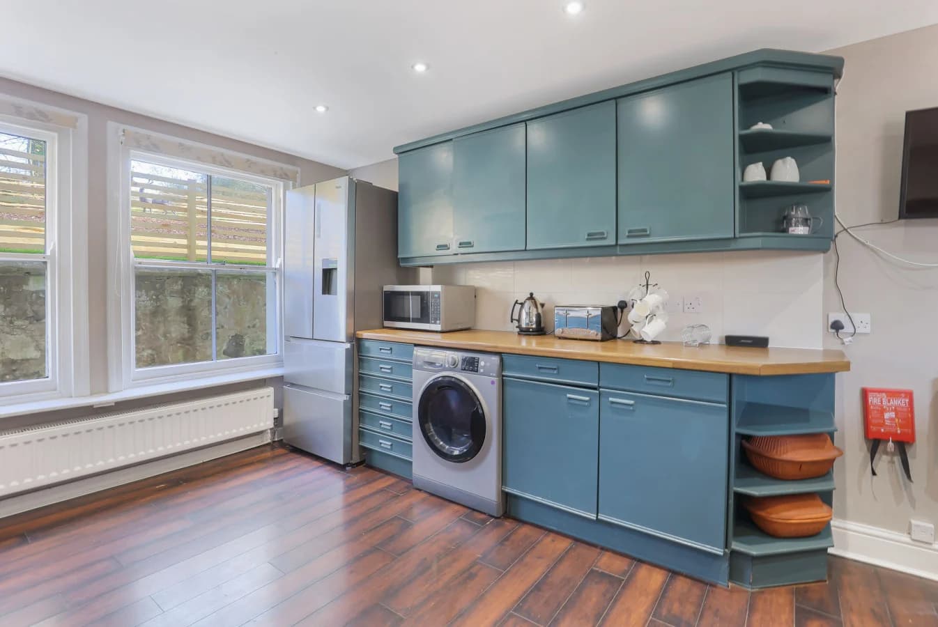 Utility kitchen area with blue cabinetry, wood worktops and garden views