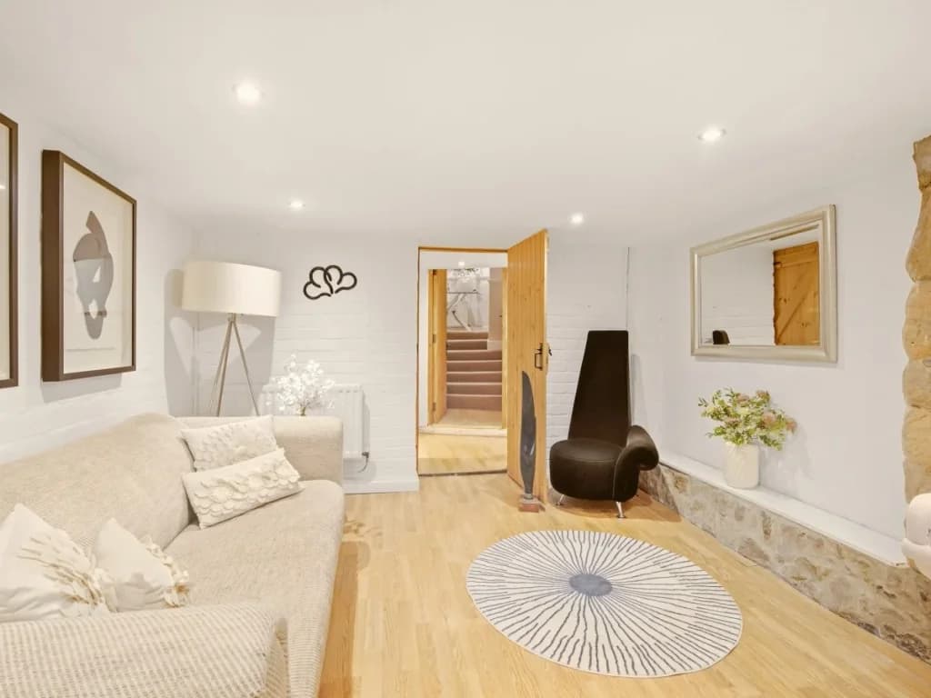 Cosy lower living area with comfortable seating and exposed stone details.