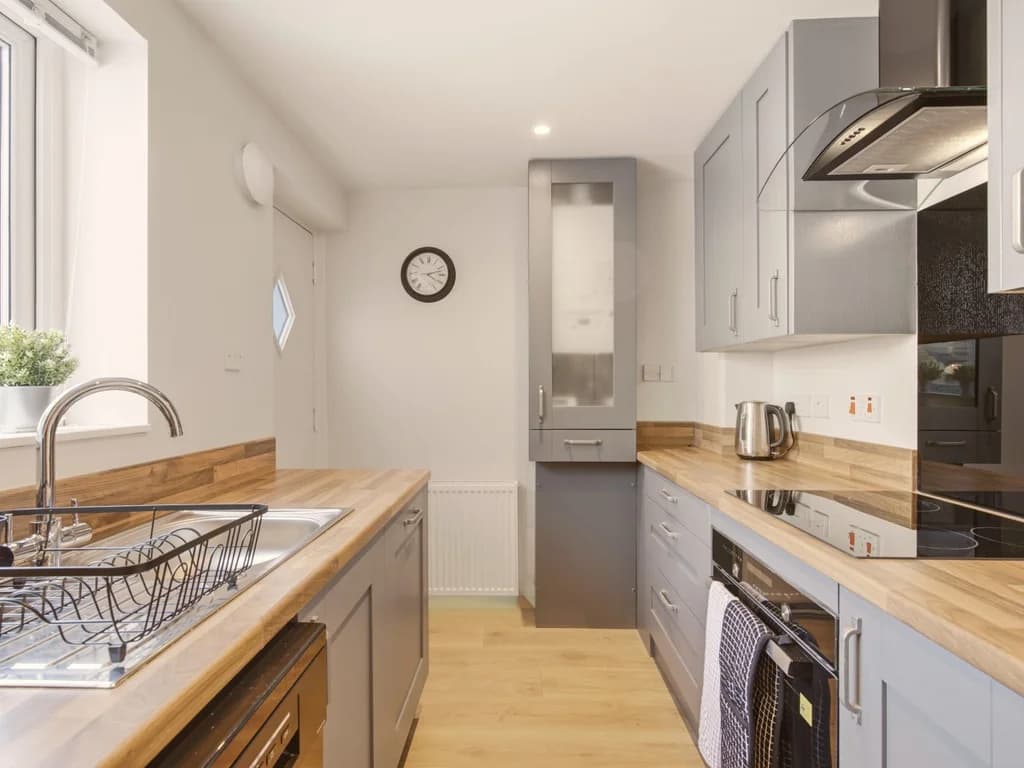 Grey kitchen with wooden worktops, integrated appliances and sink