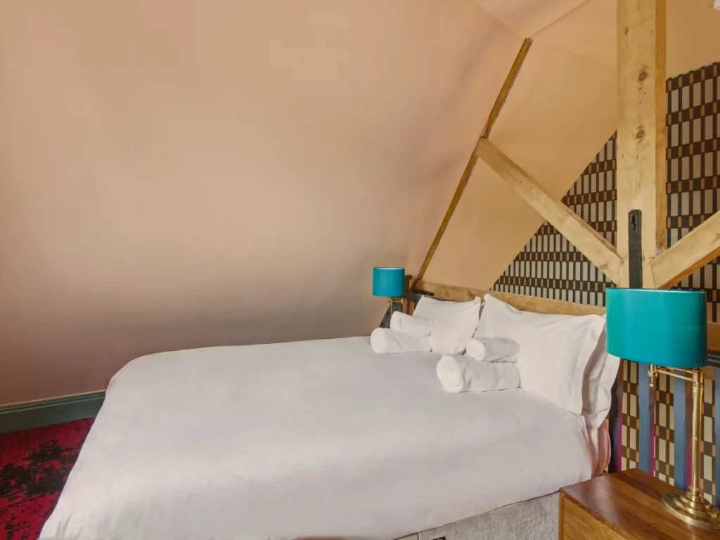 Mezzanine bedroom with double bed, exposed beams and bedside lamps