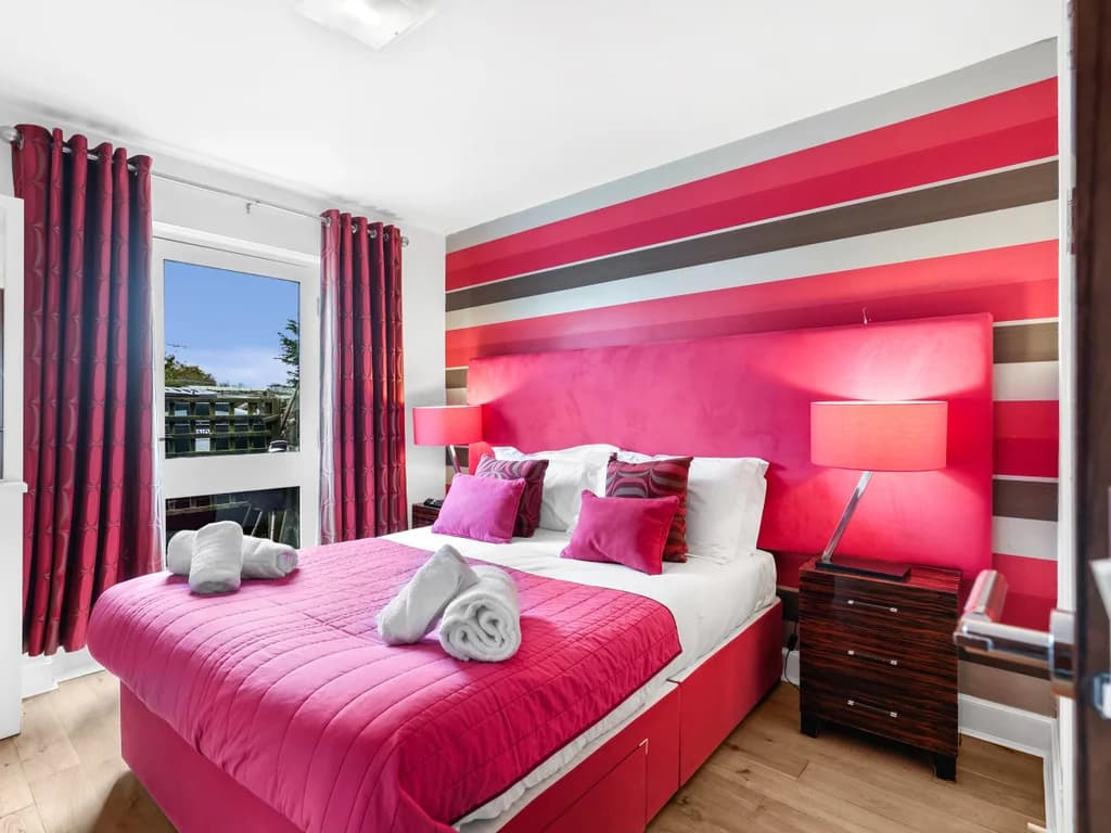 Ground-floor king bedroom with bold pink accents and ensuite access