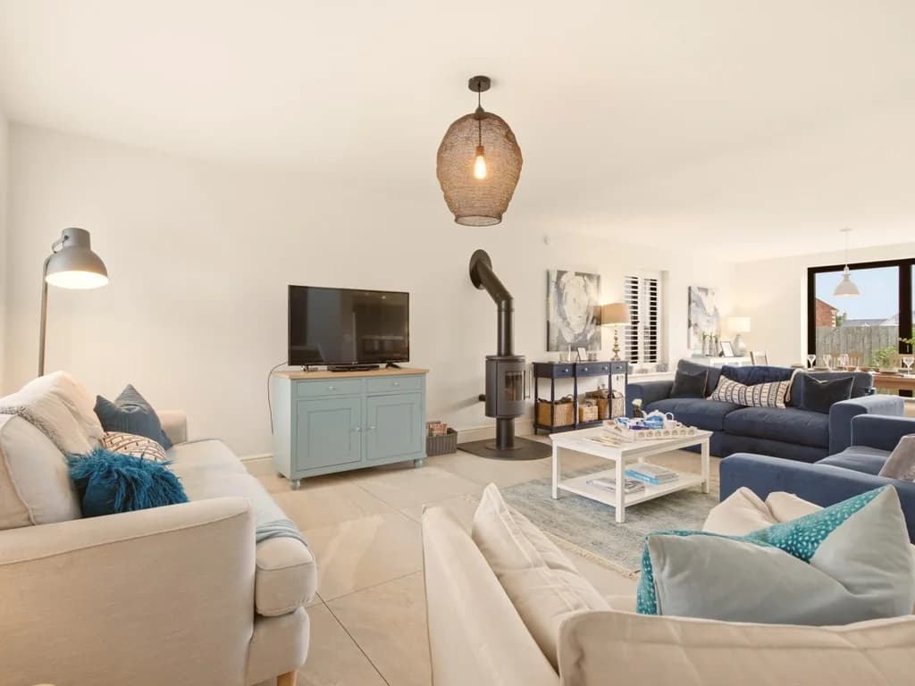 Open-plan lounge with wood burner, blue sofas and painted TV cabinet