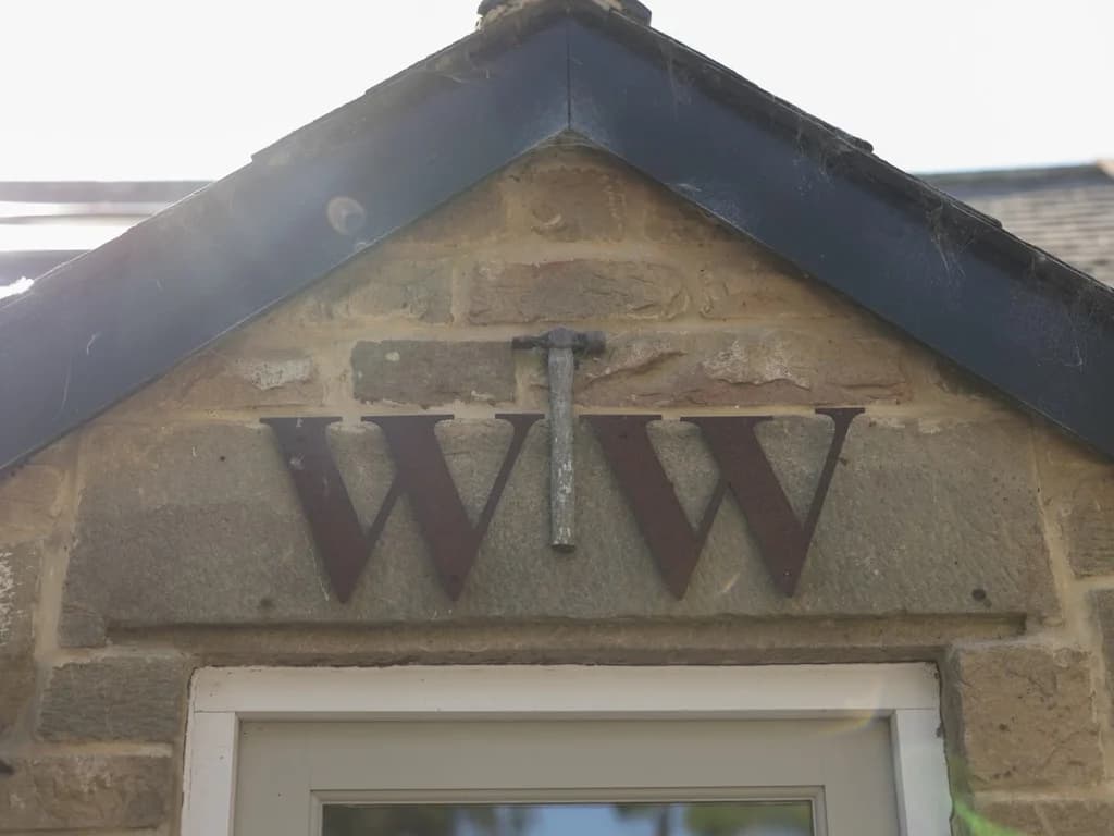 Stone entrance gable with WW initials marking Woodworkers Cottage