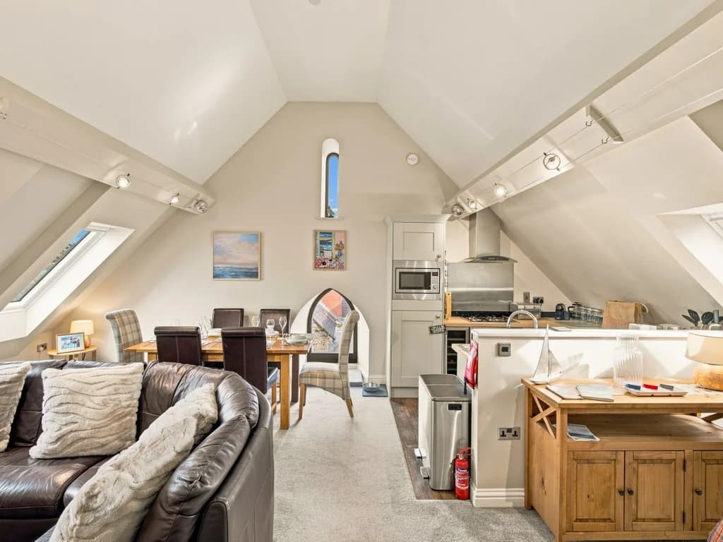 Open-plan living area with skylights, dining table and fitted kitchen.