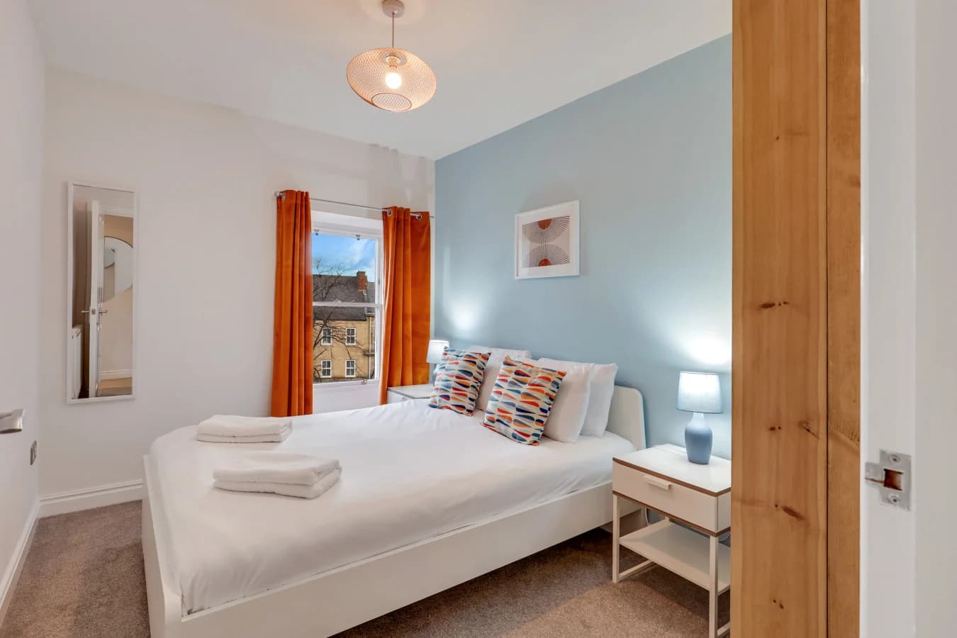 Double bedroom with soft blue walls, colourful textiles and town-centre views