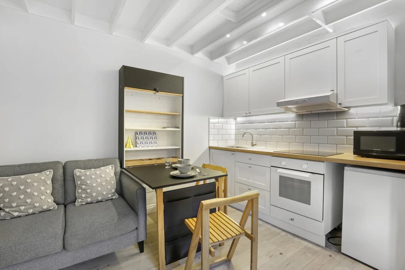 Compact studio-style living space with kitchen, dining table and sofa