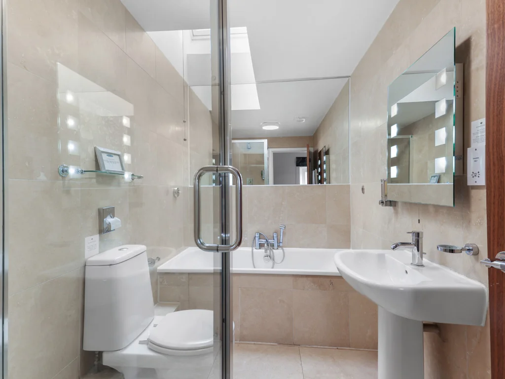 Family bathroom with bath, walk-in shower and stone tiling