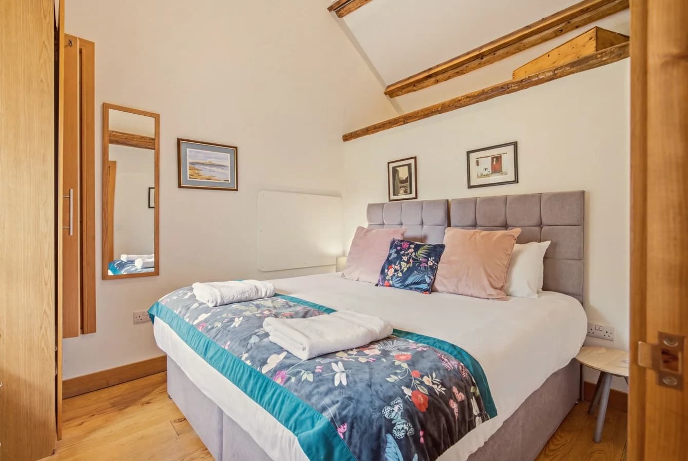 Bright bedroom with upholstered headboard and exposed timber beams