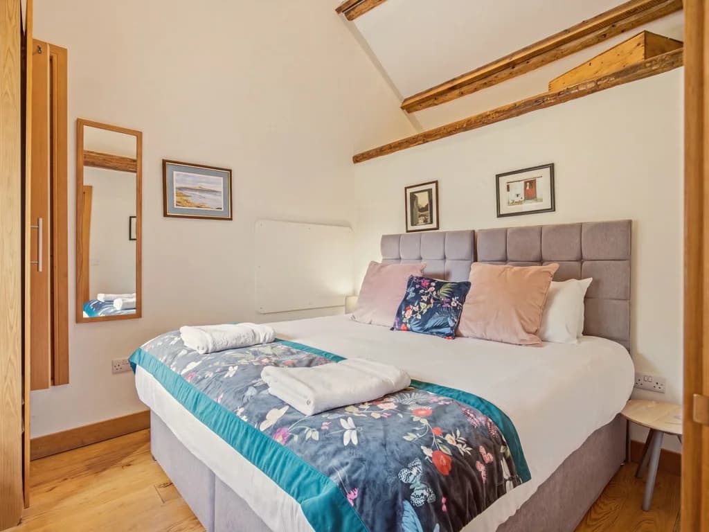 Bright bedroom with upholstered headboard and exposed timber beams