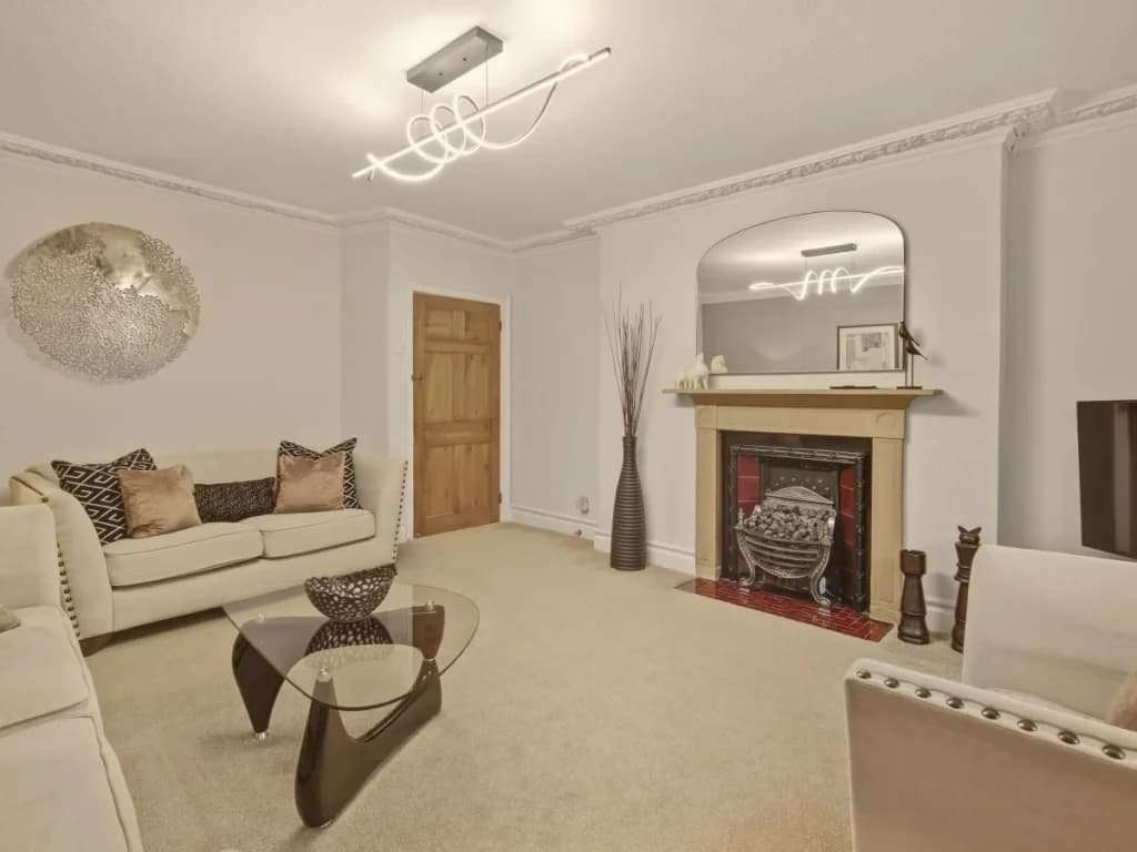 Living room with feature fireplace, large mirror and comfortable seating.