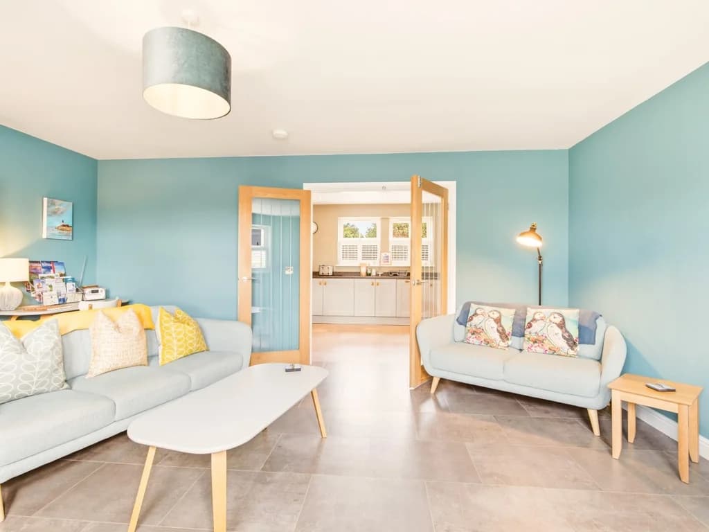 Comfortable lounge with double doors leading into the kitchen and dining area