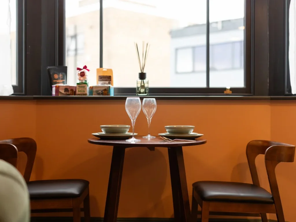 Dining table set for two beneath the bay window with city views.
