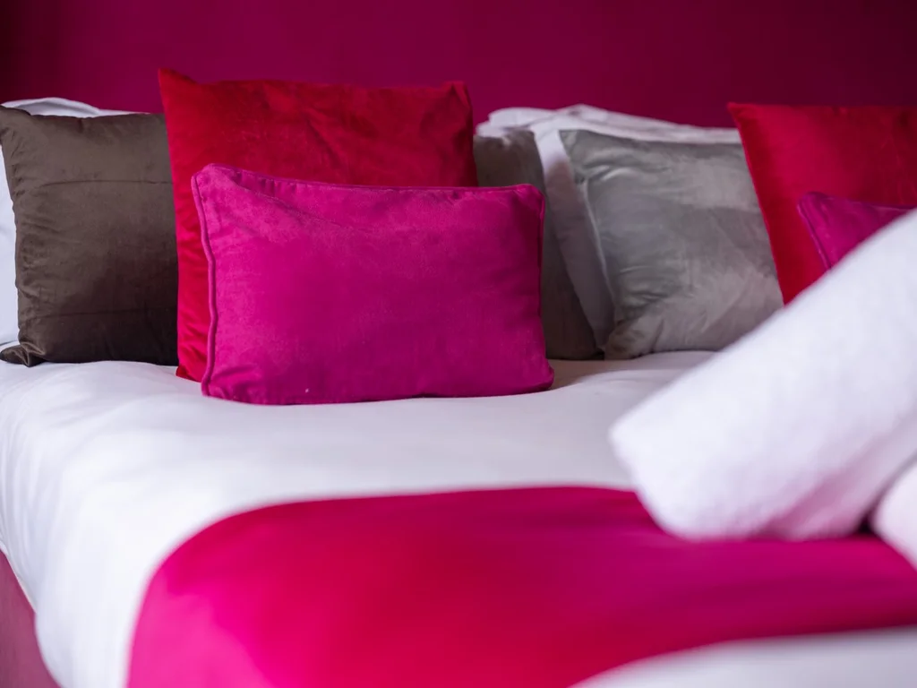 Close-up of the super-king bed with magenta linens and velvet cushions