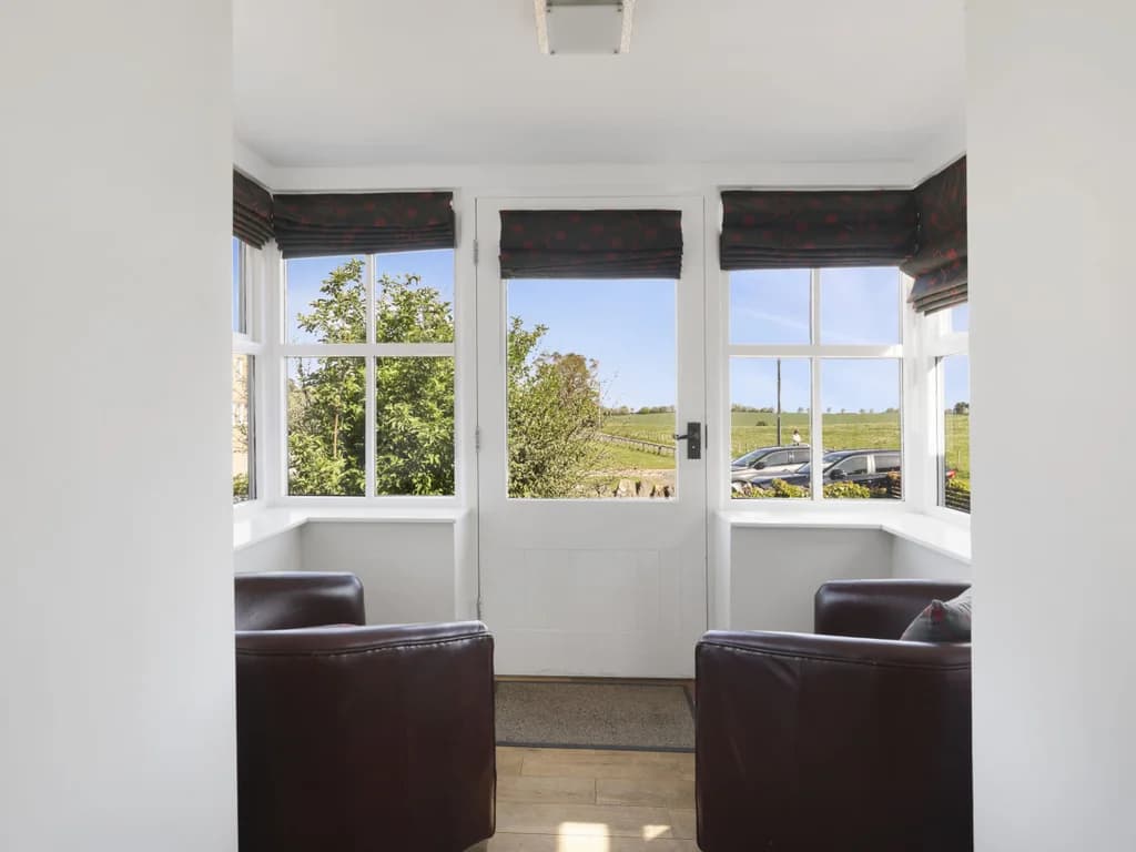 Bay window seating area with countryside views and leather chairs.