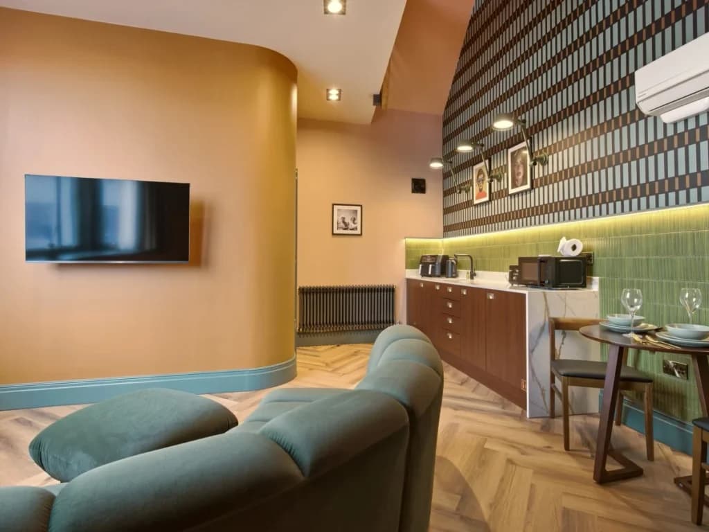 Open-plan living area with curved sofa, Smart TV and kitchenette