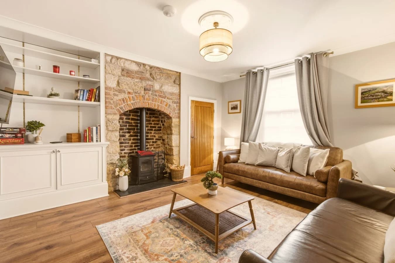 Cosy living room with wood-burning stove, leather sofas and feature fireplace.