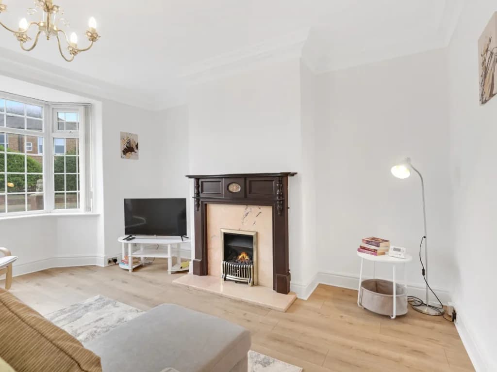 Bright living room with bay window, TV, fireplace and reading lamp