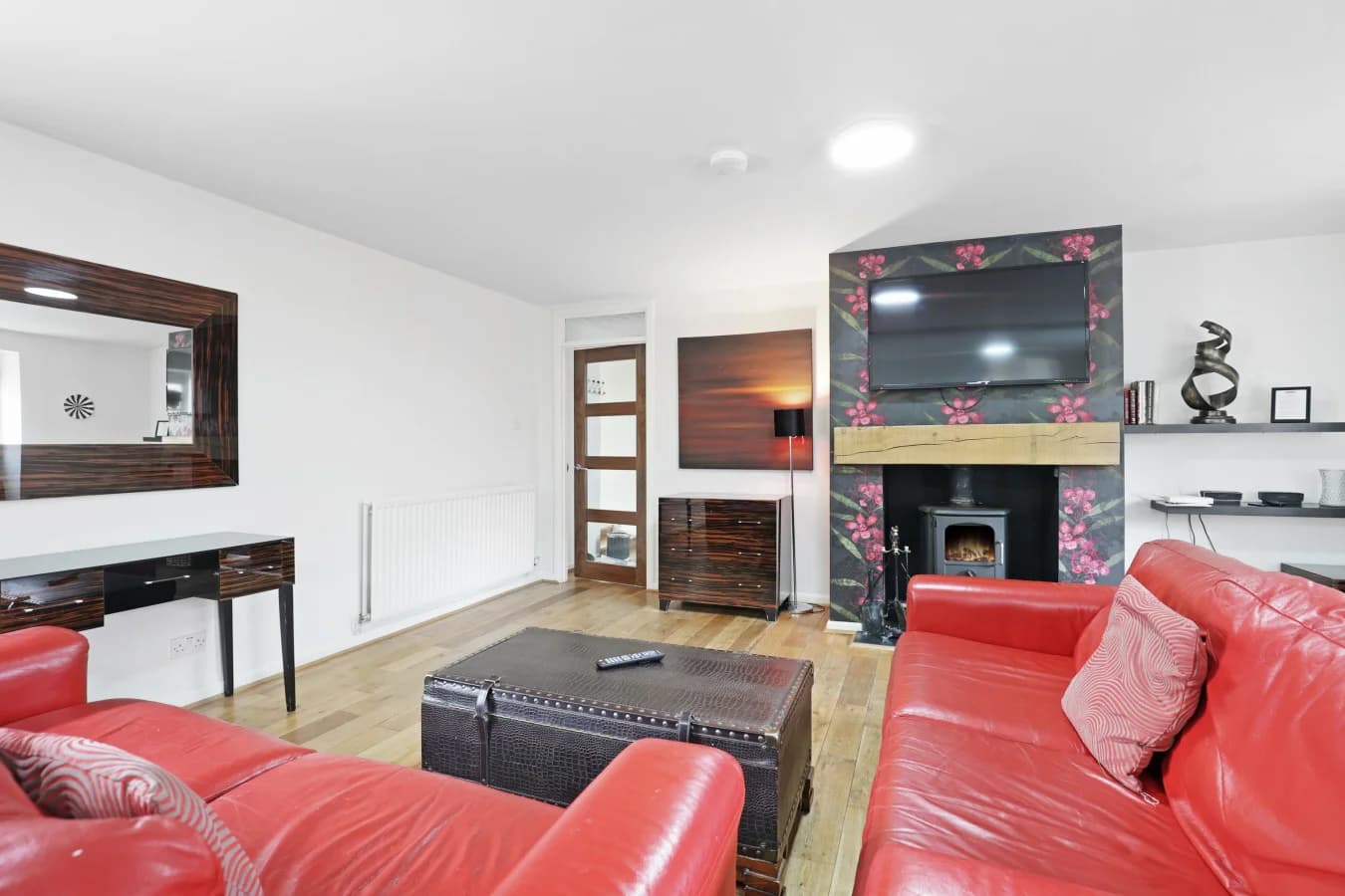 Lounge with feature fireplace, Smart TV and red leather sofas.