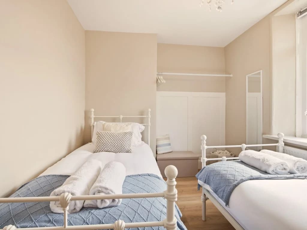 Bright twin bedroom with two single beds and large window.