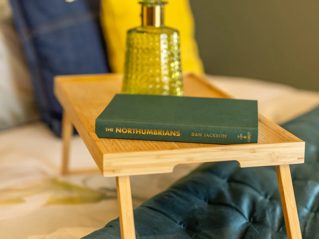 Local heritage reading — 'The Northumbrians' on the bed tray.