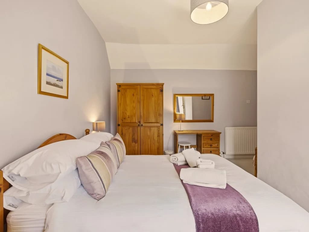 Spacious double bedroom with dressing table, oak wardrobe and bedside lighting