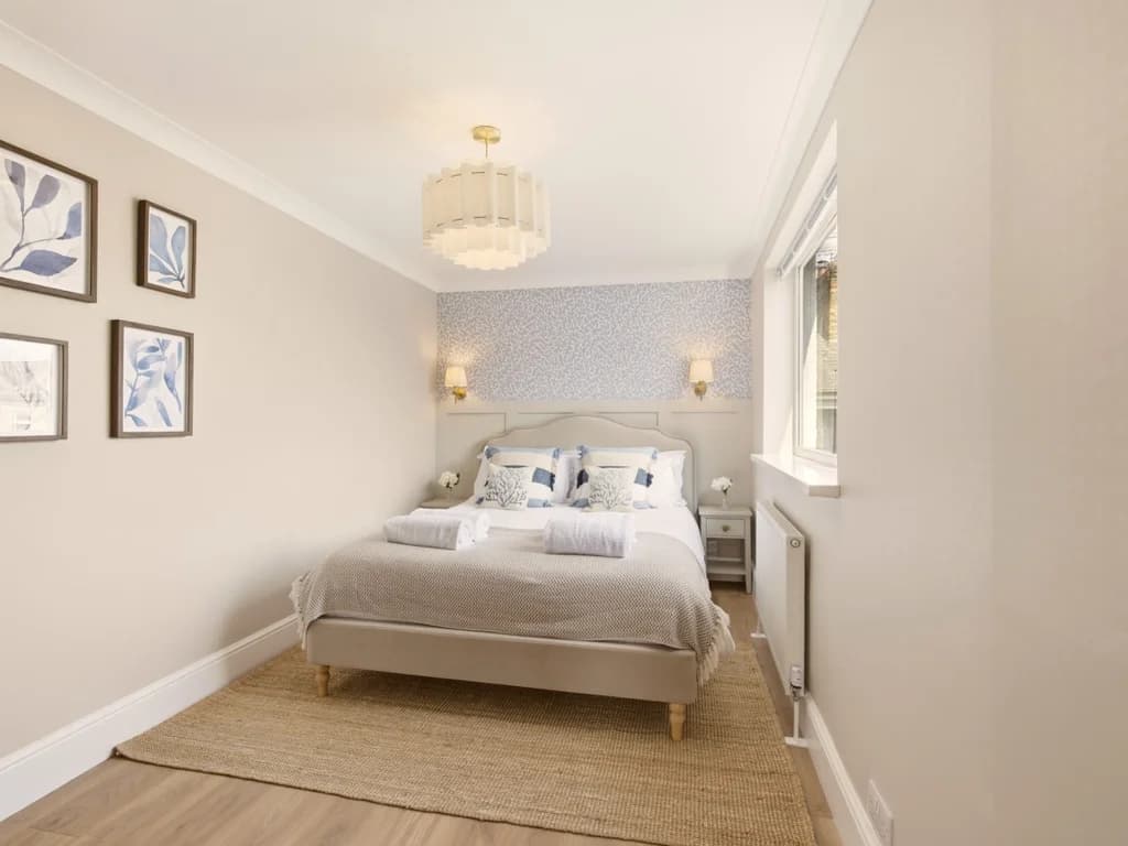 Double bedroom with grey upholstered bed and feature wallpaper