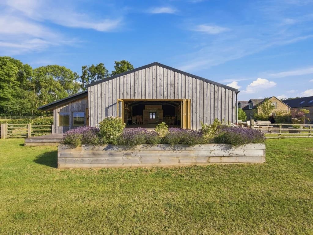 Timber-clad barn exterior with wide doors and raised planting beds