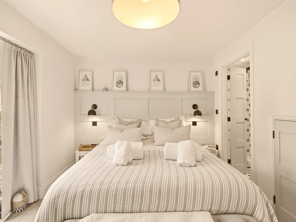Bright king bedroom with striped bedding, bedside lighting and French doors