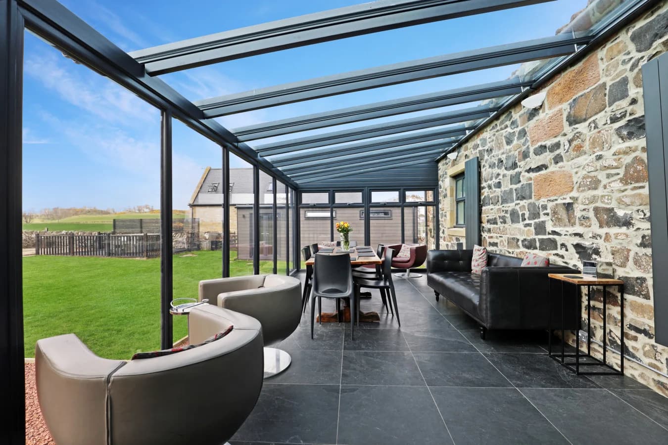 Conservatory with seating, dining table and exposed stone wall
