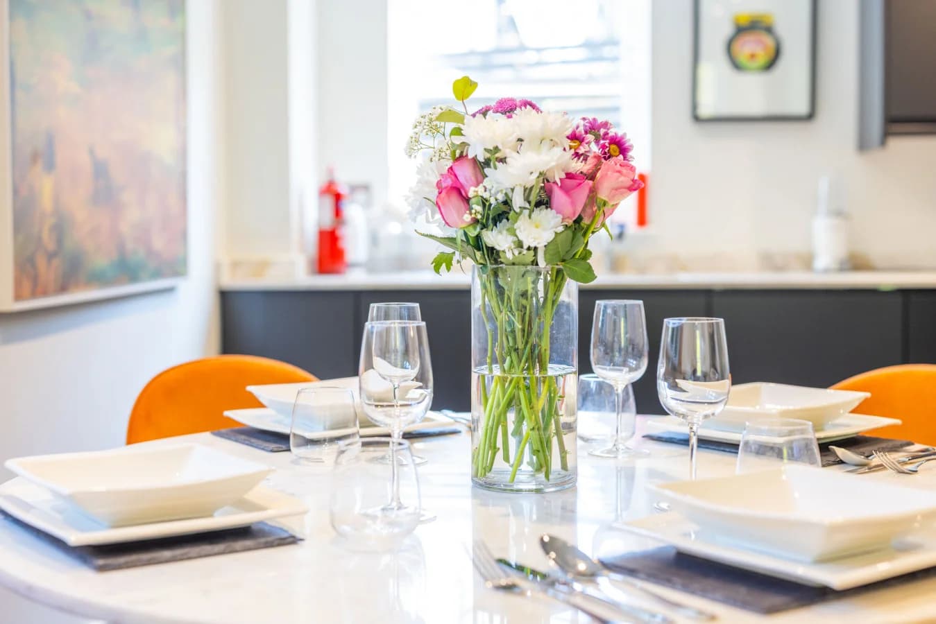 Quartz dining table with floral centrepiece and orange chairs