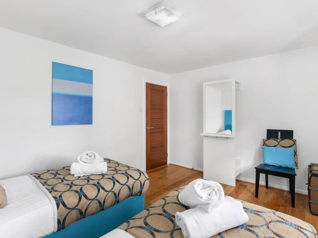 Twin bedroom with turquoise accents, vanity desk and oak flooring