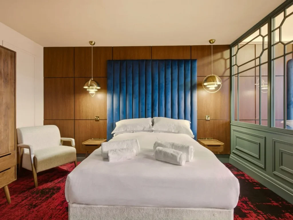 Double bed framed by wood panelling with seating and feature screen.