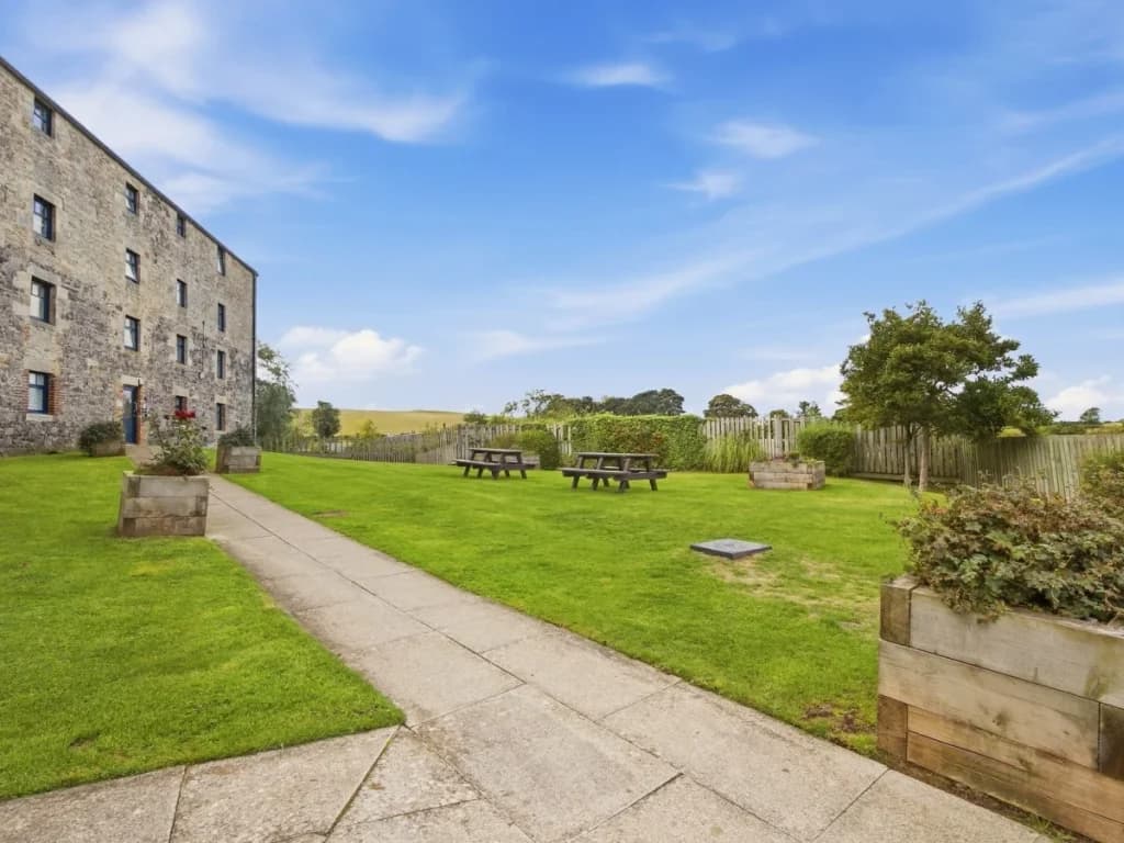 Shared garden with picnic tables, open lawns and countryside beyond