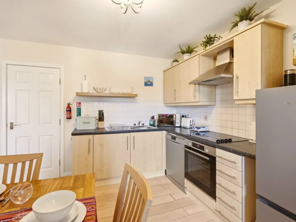 Bright kitchen with ample cabinetry, oven, hob and full-size fridge freezer