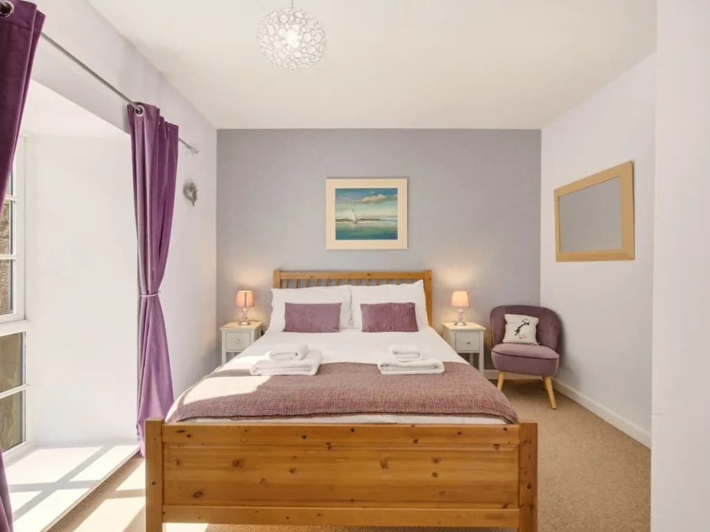 King bedroom with wooden bed frame, bedside tables and purple accents