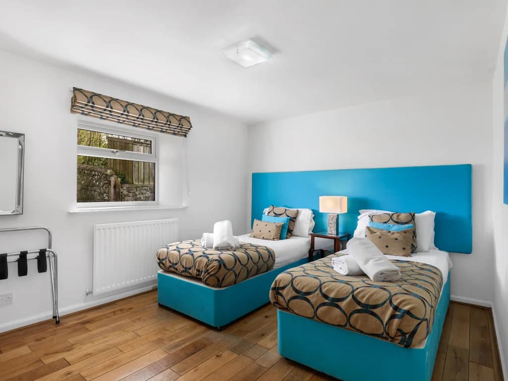 Twin bedroom with turquoise headboards and oak flooring