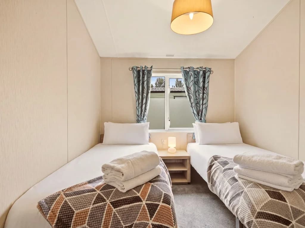 Twin bedroom with matching single beds and bedside table by the window