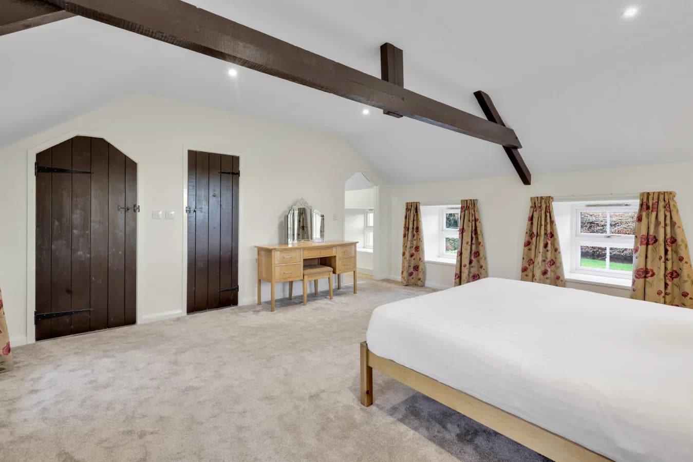 Spacious king bedroom beneath vaulted ceilings and exposed beams