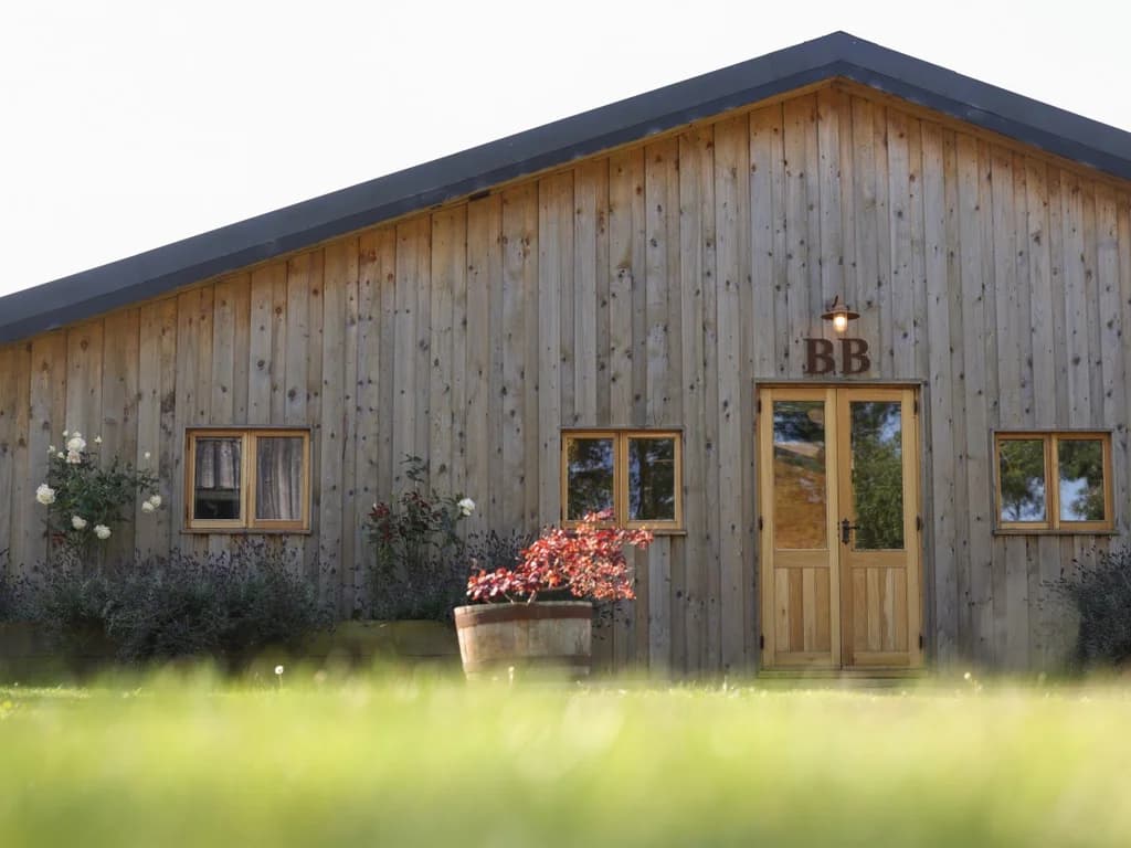 Characterful Big Barn entrance with timber cladding and floral planters
