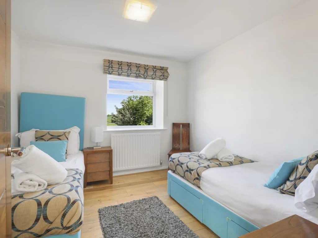 Twin bedroom with blue upholstered beds and hardwood flooring