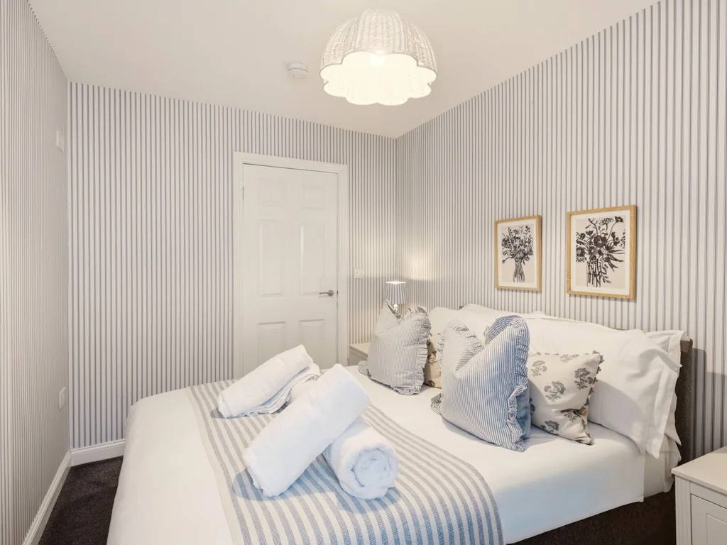 Alternate view of the double bedroom with hanging rail and bedside lamps.
