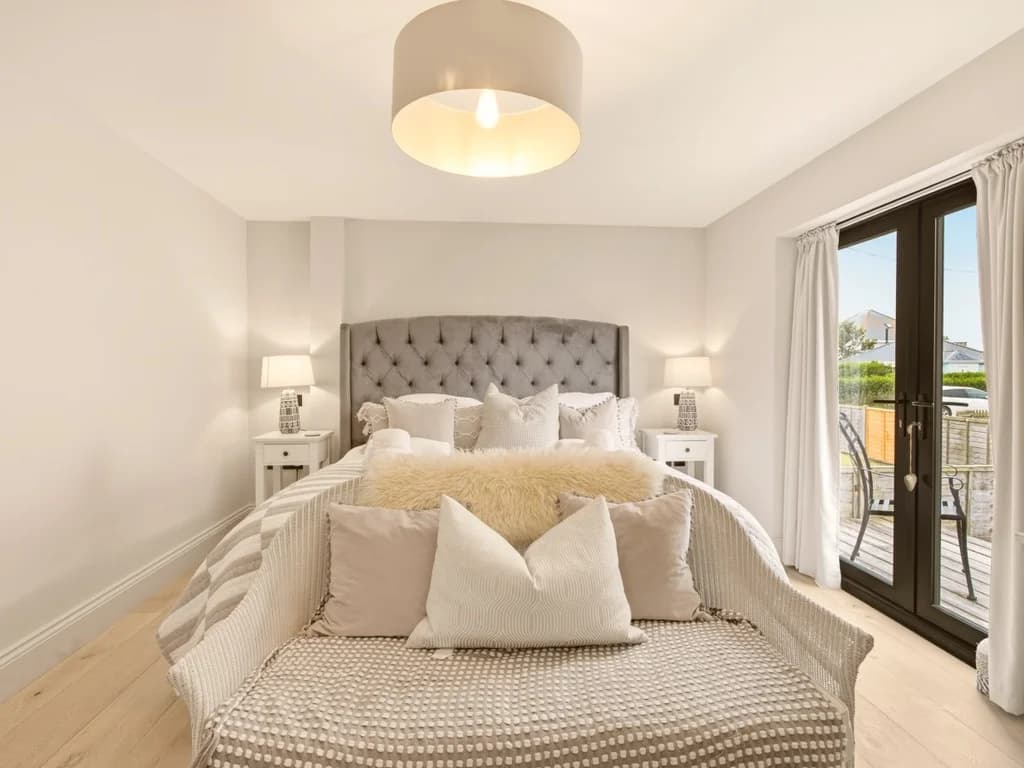 King bedroom with French doors, upholstered headboard and neutral décor