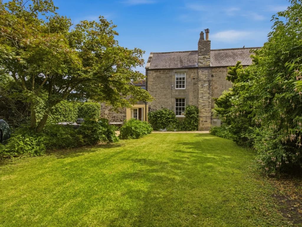 Rear garden with mature landscaping and peaceful views of the stone cottage
