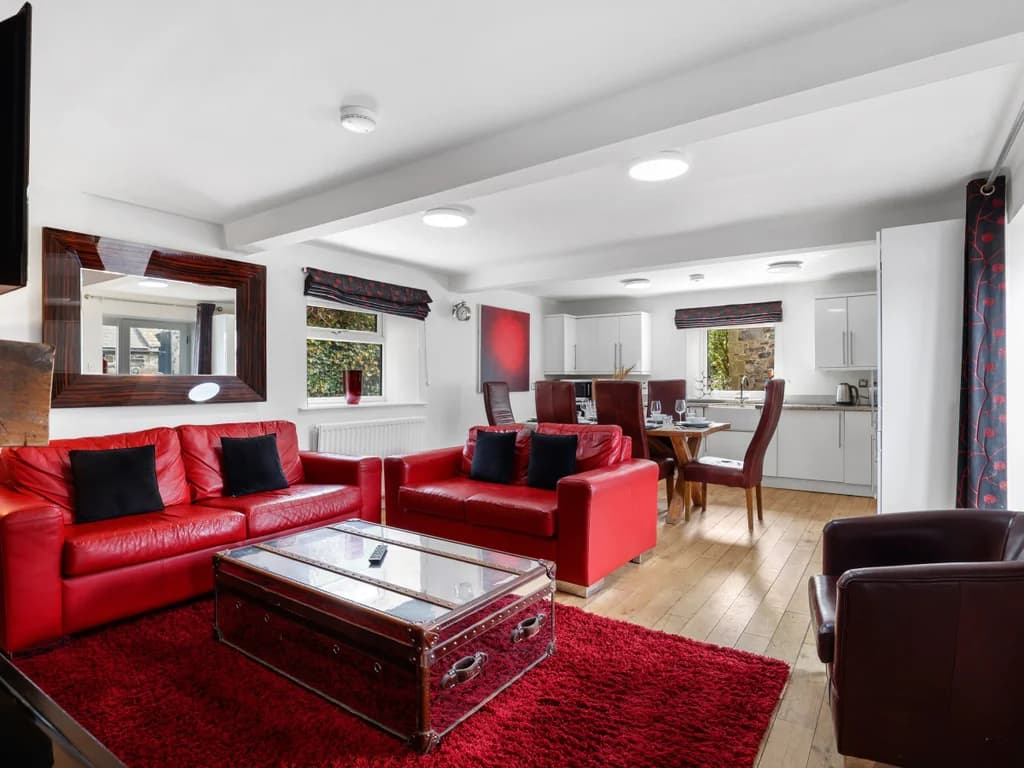 Open-plan lounge with red leather sofas and oak flooring