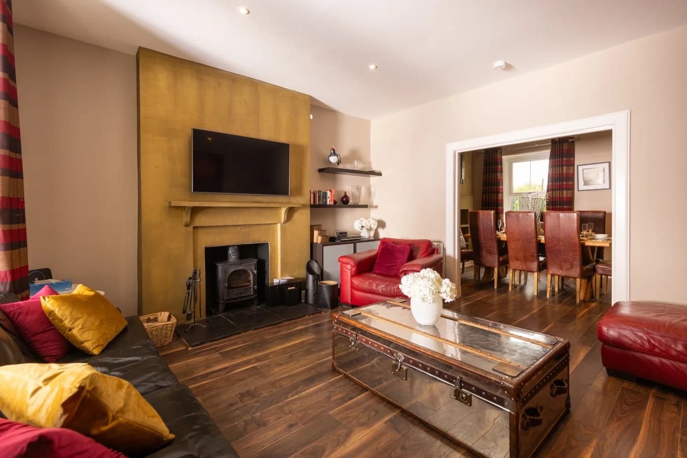 Living room with red leather seating and oak flooring