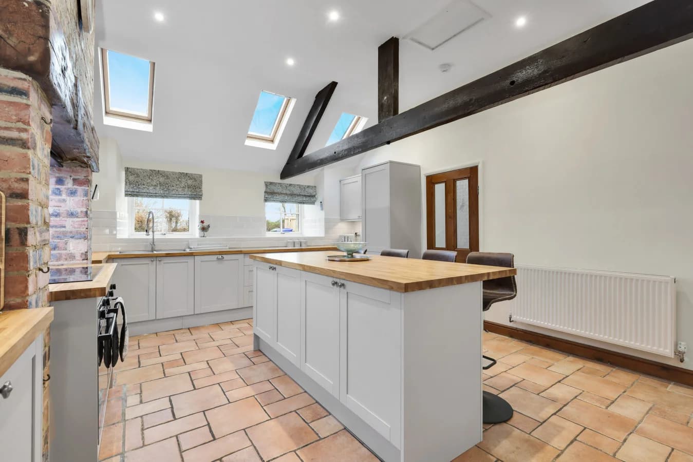 Open-plan kitchen with vaulted ceiling and rustic tiled flooring