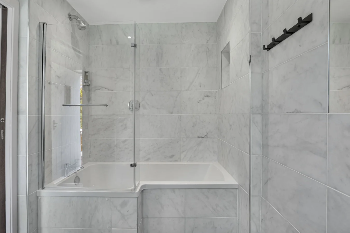 Family bathroom with bath-shower and marble-effect wall tiles